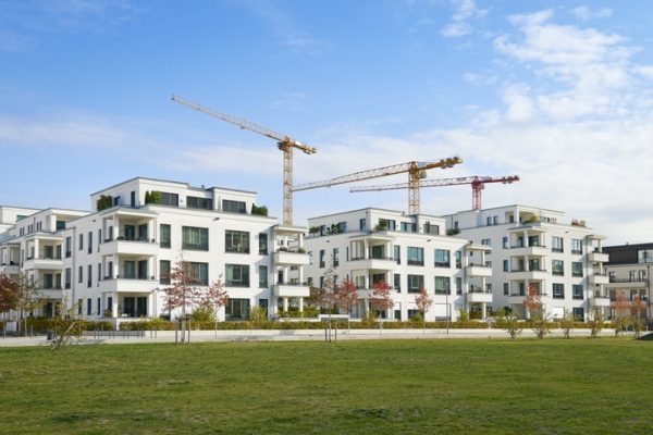 Brand new luxury townhouses and clear sky in Duesseldorf, Germany, three cranes of a construction area behind the buildings.